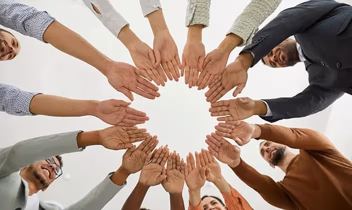 A picture of a team joining hands together in a circle